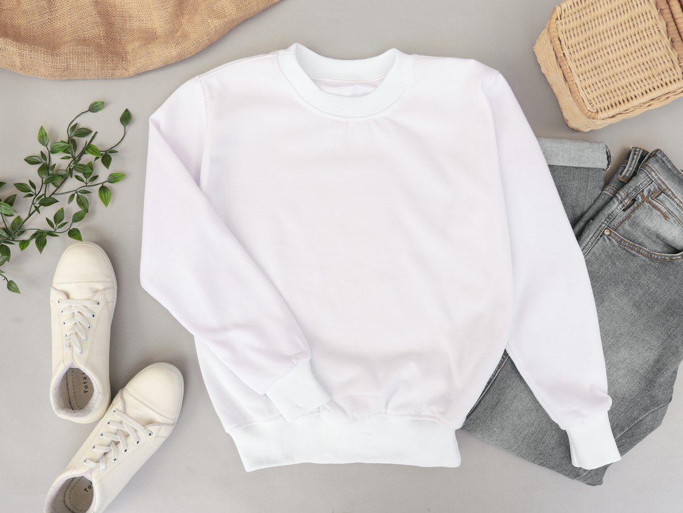 A crewneck sweatshirt laid out with jeans and sneakers
